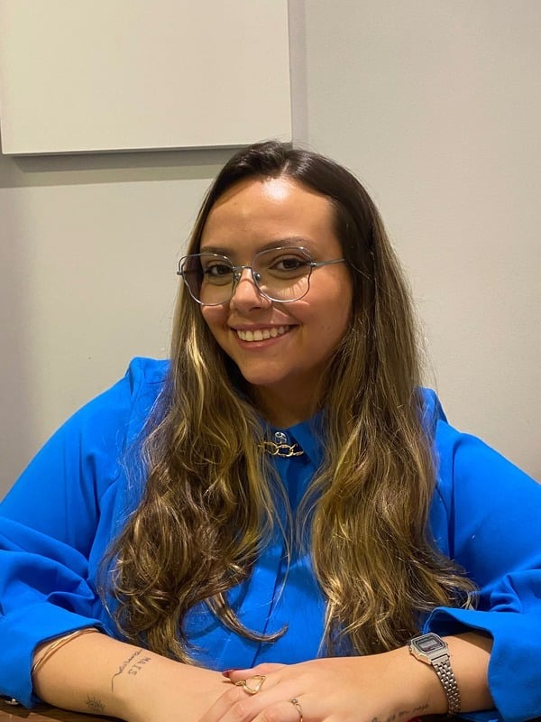 Nicole P. P. Factori, psicóloga clínica, sorrindo em seu consultório